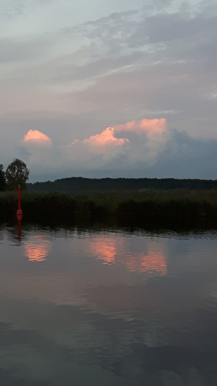 REFLECTION OF MAN IN LAKE AGAINST SKY DURING SUNSET