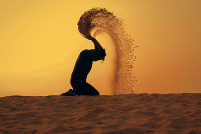 Silhouette man standing on beach against sky during sunset