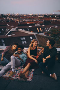 High angle view of friends relaxing together on terrace in city during rooftop party