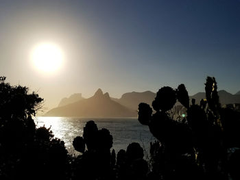 Silhouette people by sea against sky during sunset