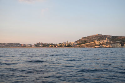 Sea by buildings against clear sky