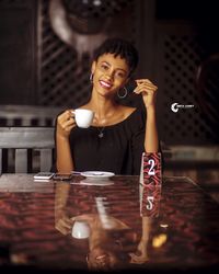 Portrait of a smiling young woman sitting on table