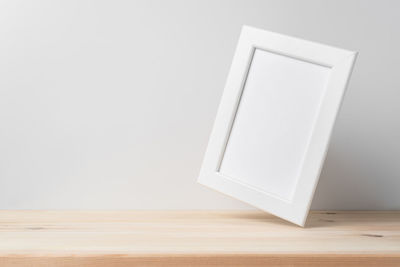 Close-up of wooden table against white wall