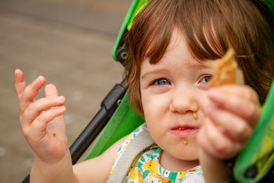 Close-up portrait of baby girl holding food on carriage