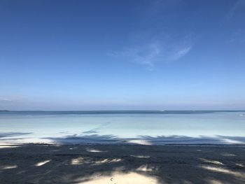 Scenic view of beach against blue sky