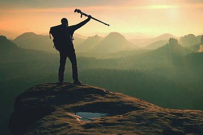 Tourist with medicine crutch above head achieved mountain peak. broken leg immobilizer. hand in air