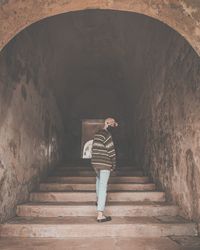 Rear view of woman standing by staircase