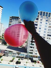 Low angle view of balloons against buildings in city