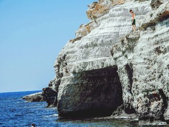 Low angle view of rock formation by sea against clear sky