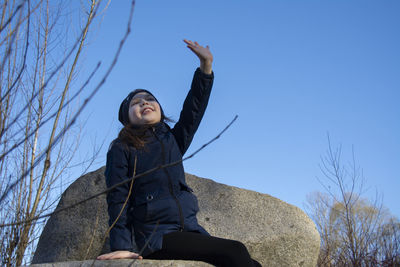 Low angle view of woman looking at camera against clear blue sky