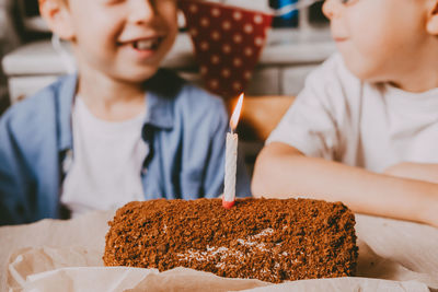 Sweet roll with chocolate filling and holiday candles and happy children on a neutral background.