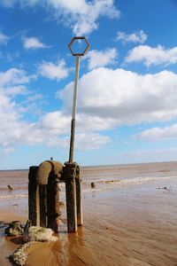 Cross on beach against sky