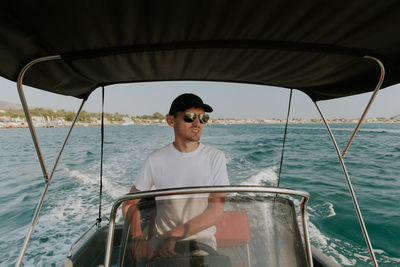 A young guy controls a boat on the sea.