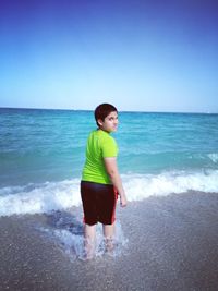 Full length of boy standing on beach against sky