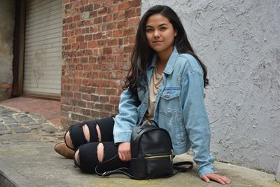 Portrait of beautiful woman sitting on walkway