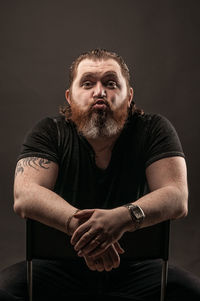 Portrait of mid adult man sitting against black background