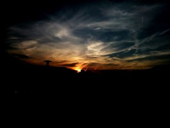 Silhouette landscape against dramatic sky during sunset