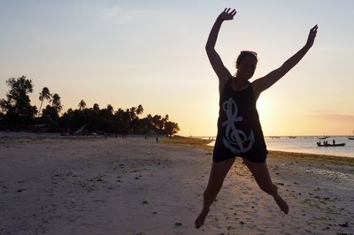 People jumping on beach at sunset