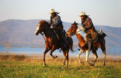 Men riding horse on grass