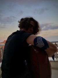 Rear view of woman standing against sky during sunset