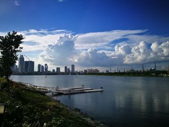 City at waterfront against cloudy sky