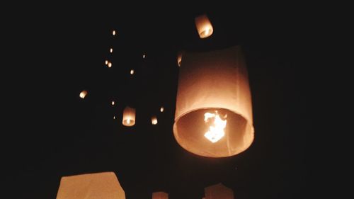 Low angle view of illuminated light bulb against sky at night