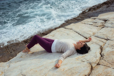 High angle view of woman lying on rock at beach