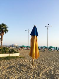 Beach umbrellas by sea against clear sky