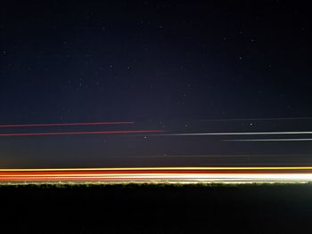 Light trails on road against sky at night