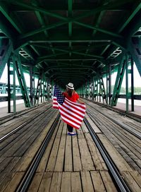 Rear view of woman standing on bridge 