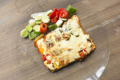 Italian food known as lasagna on a glass plate and a wooden background.