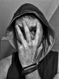 Close-up portrait of man in hooded shirt covering face