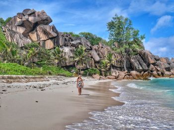 Full length of man on rock at beach against sky