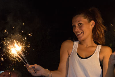 Close-up of woman holding sparkler at night