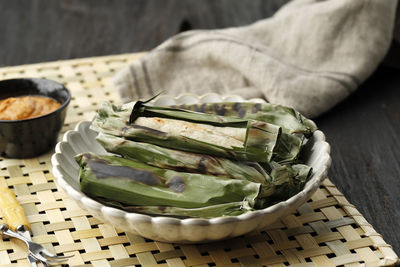 Grilled otak otak indonesian fish cake wrapped with banana leaf and grill. served with peanut sauce 