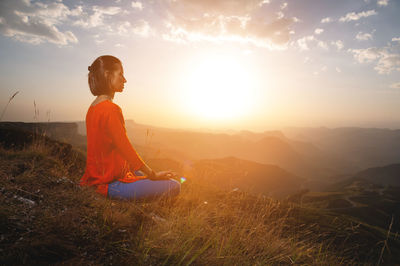 Woman practices yoga and meditates on a mountain. side view of a yogi practicing in the mountains at