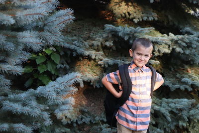 Portrait of boy standing against trees