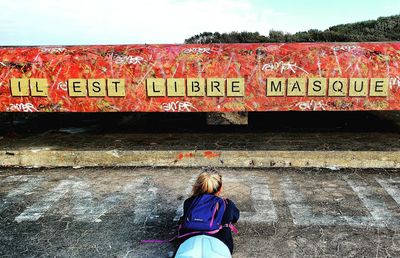 Rear view of woman with text on wall