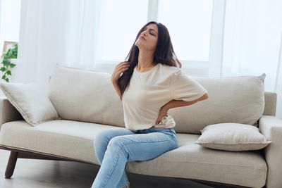 Young woman using mobile phone while sitting on sofa at home