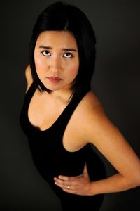 Portrait of young woman standing against black background
