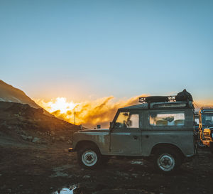 Car on land against sky during sunset