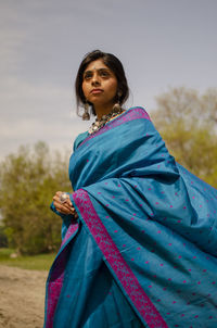 Portrait of beautiful young woman standing against sky