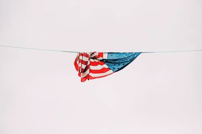 Low angle view of american flag hanging from rope against clear sky