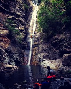 People on waterfall by cliff