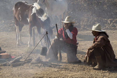 Full length of cowboys with horse on field