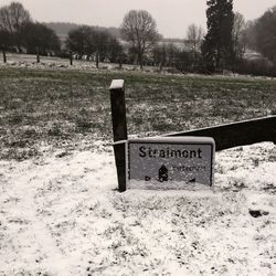 Information sign on snow field against sky during winter