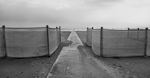Footpath leading towards beach against sky