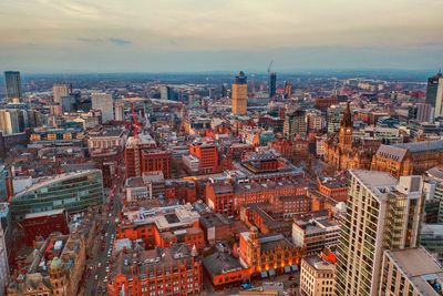 High angle view of city buildings against cloudy sky