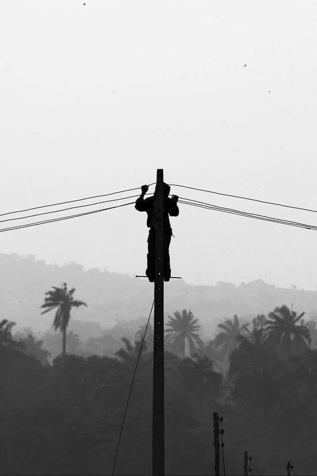 LOW ANGLE VIEW OF SILHOUETTE MAN AND ELECTRICITY PYLON AGAINST SKY