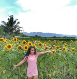 Portrait of woman with arms outstretched standing at sunflower farm